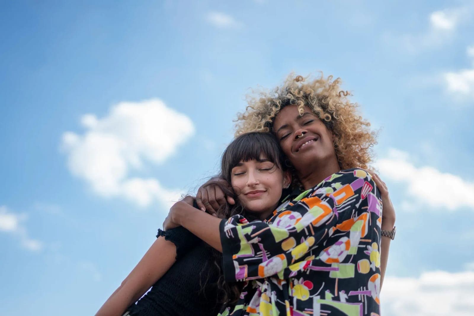 Two people sharing a warm embrace under a bright sky